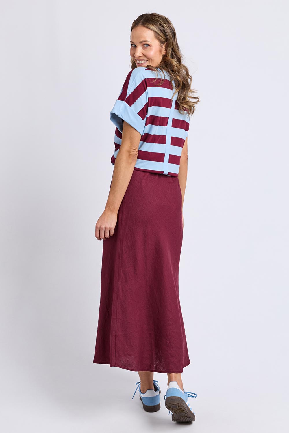A model wearing the Eleni Linen Skirt in colour Plum (Red), from the back