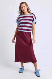 A model wearing the Eleni Linen Skirt in colour Plum (Red), from the front, showing the whole outfit