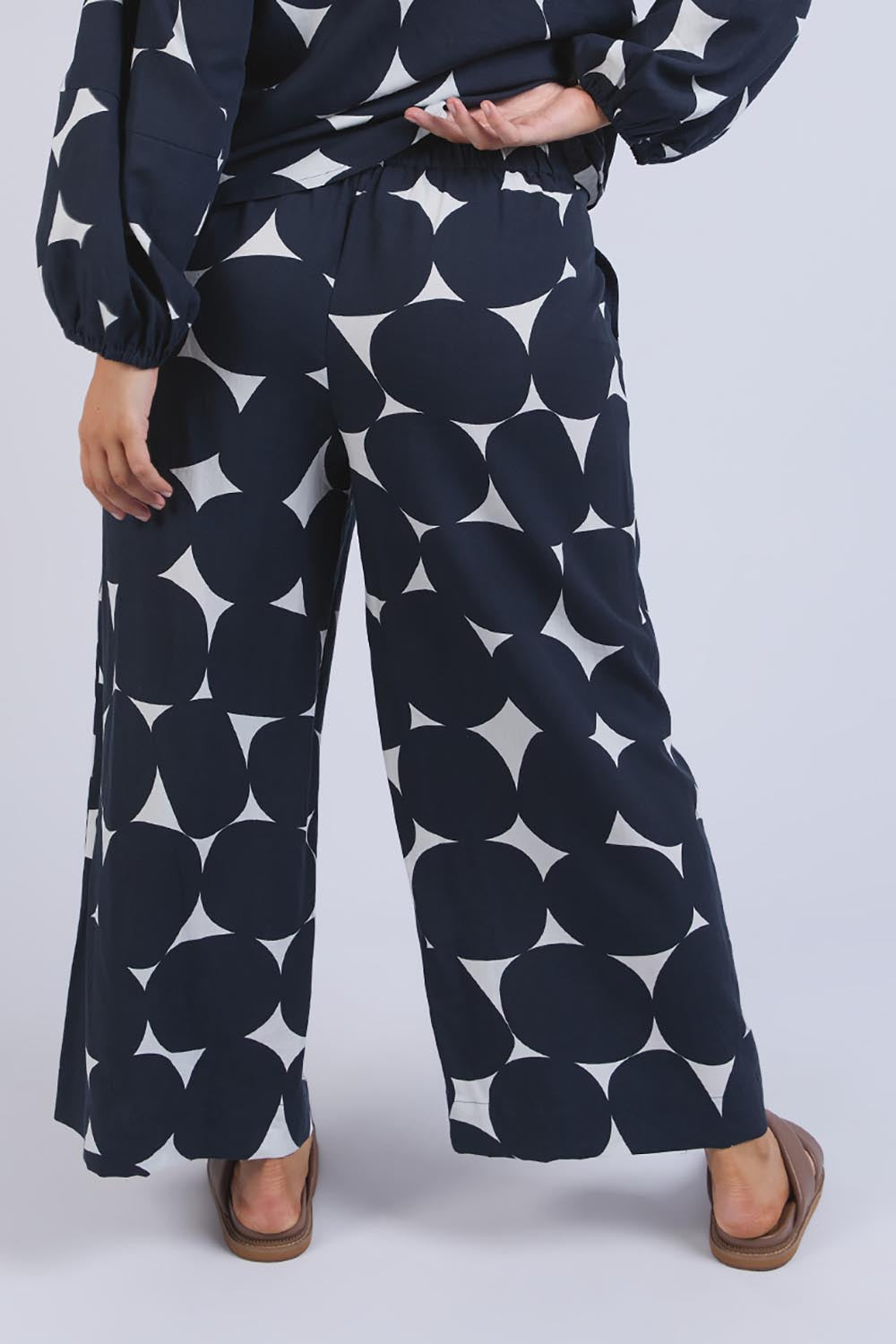 A model wearing the Demi Spot Lyocell Linen Pant in colour Spotprint (Blue), from the back