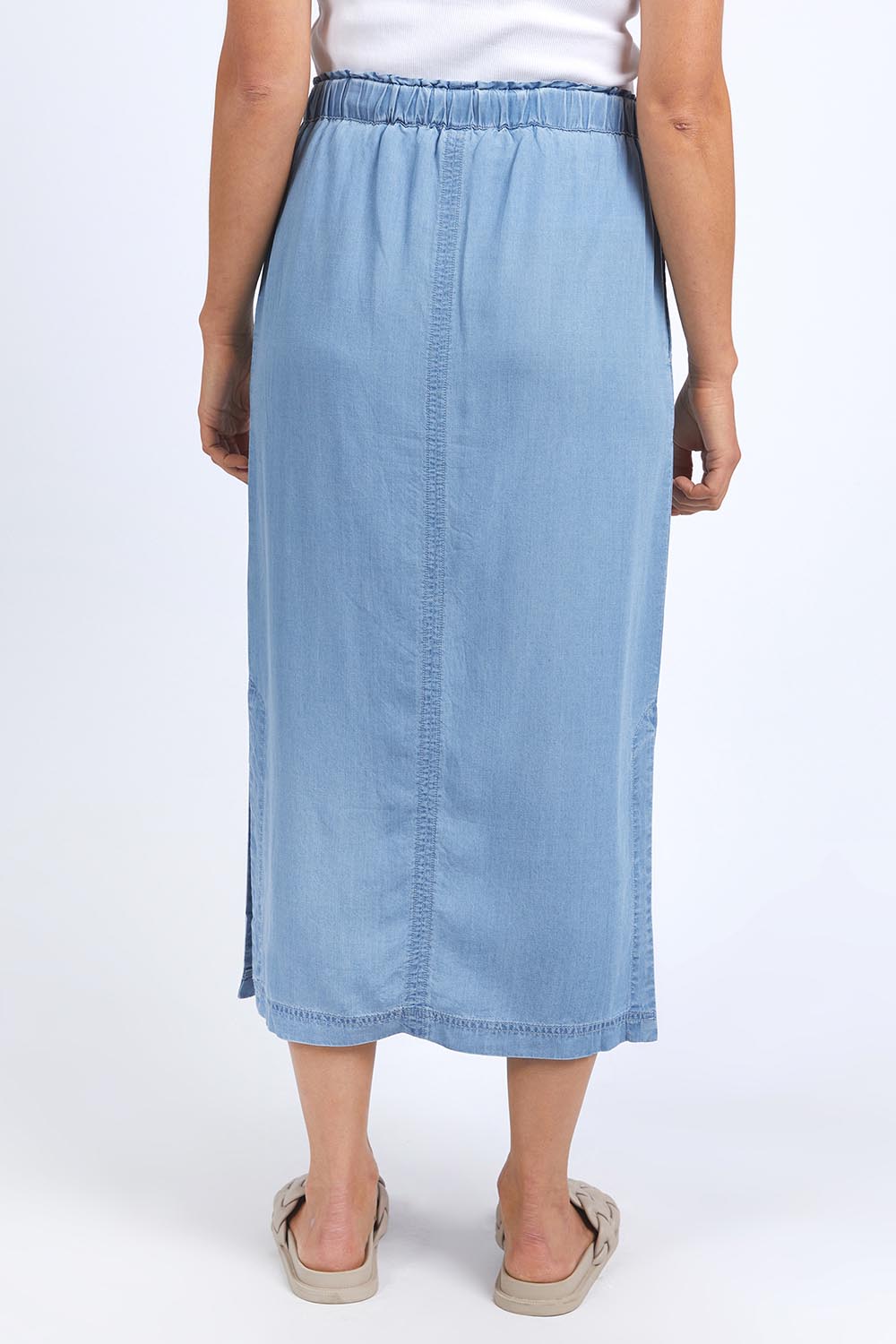 A model wearing the Penny Chambray Utility Skirt in colour Midblue (Blue), from the back