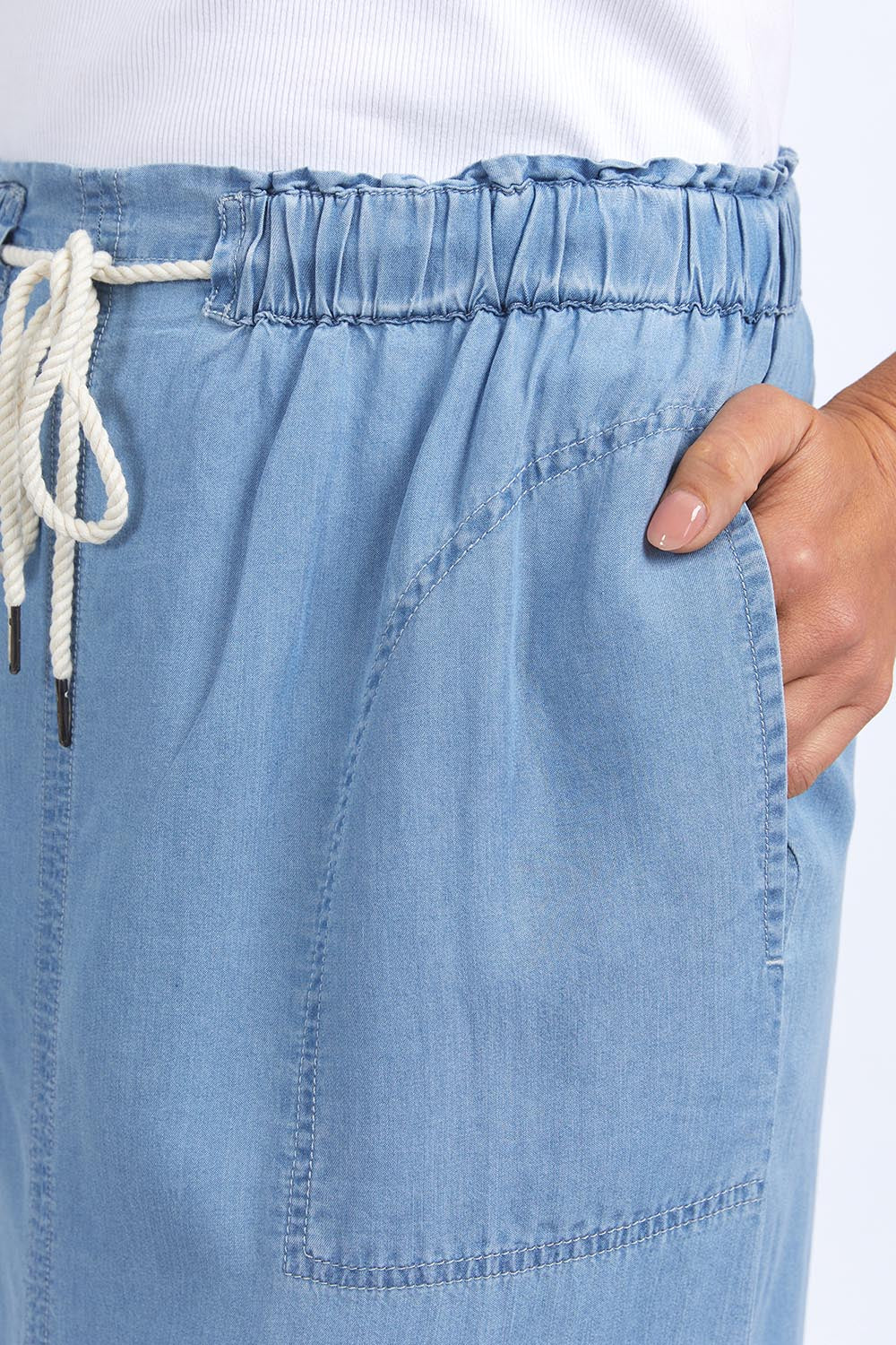 A model wearing the Penny Chambray Utility Skirt in colour Midblue (Blue), from the front, cropped image