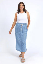 A model wearing the Penny Chambray Utility Skirt in colour Midblue (Blue), from the front, showing the whole outfit