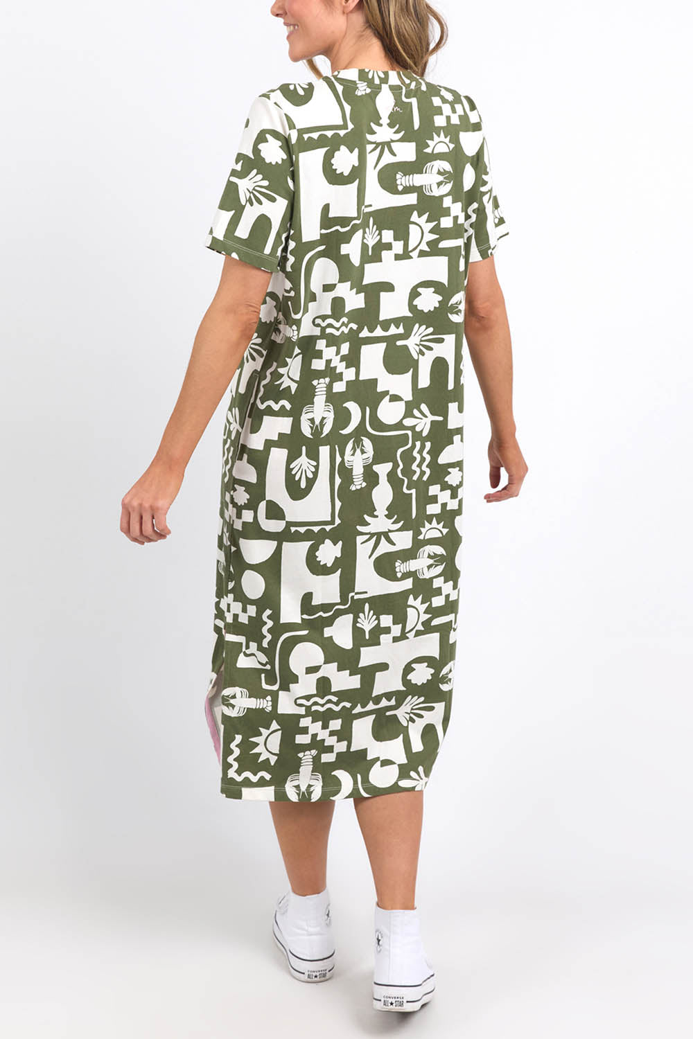 A model wearing the Postcard Tee Dress Clover in colour Clover (Green), from the back