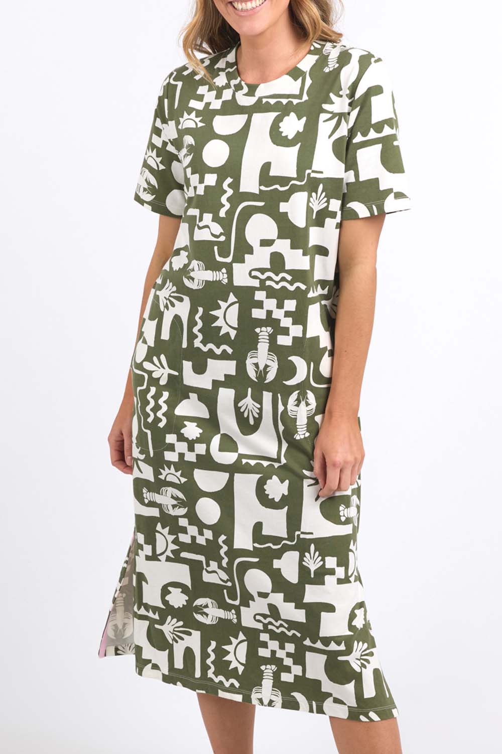 A model wearing the Postcard Tee Dress Clover in colour Clover (Green), from the front, cropped image