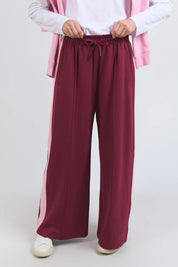 A model wearing the Carmen Wide Leg Pant in colour Merlot (Red), from the front, cropped image
