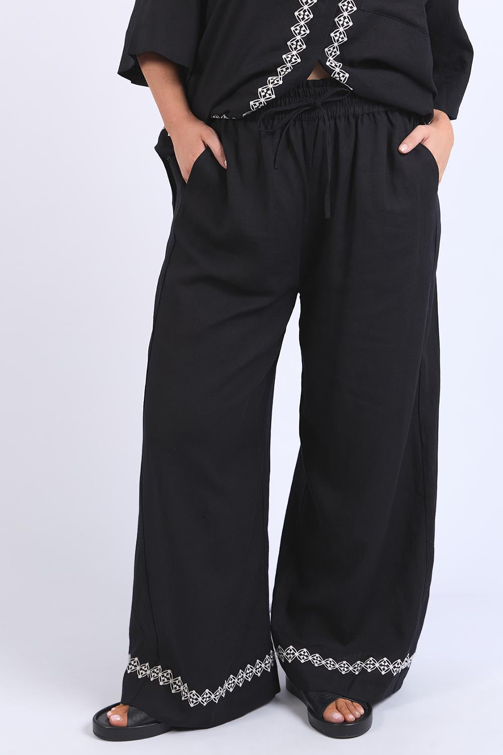 A model wearing the Nina Embroidered Pant in colour Black (Black), from the front, cropped image