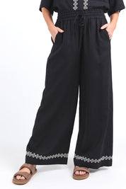 A model wearing the Nina Embroidered Pant in colour Black (Black), from the front, cropped image