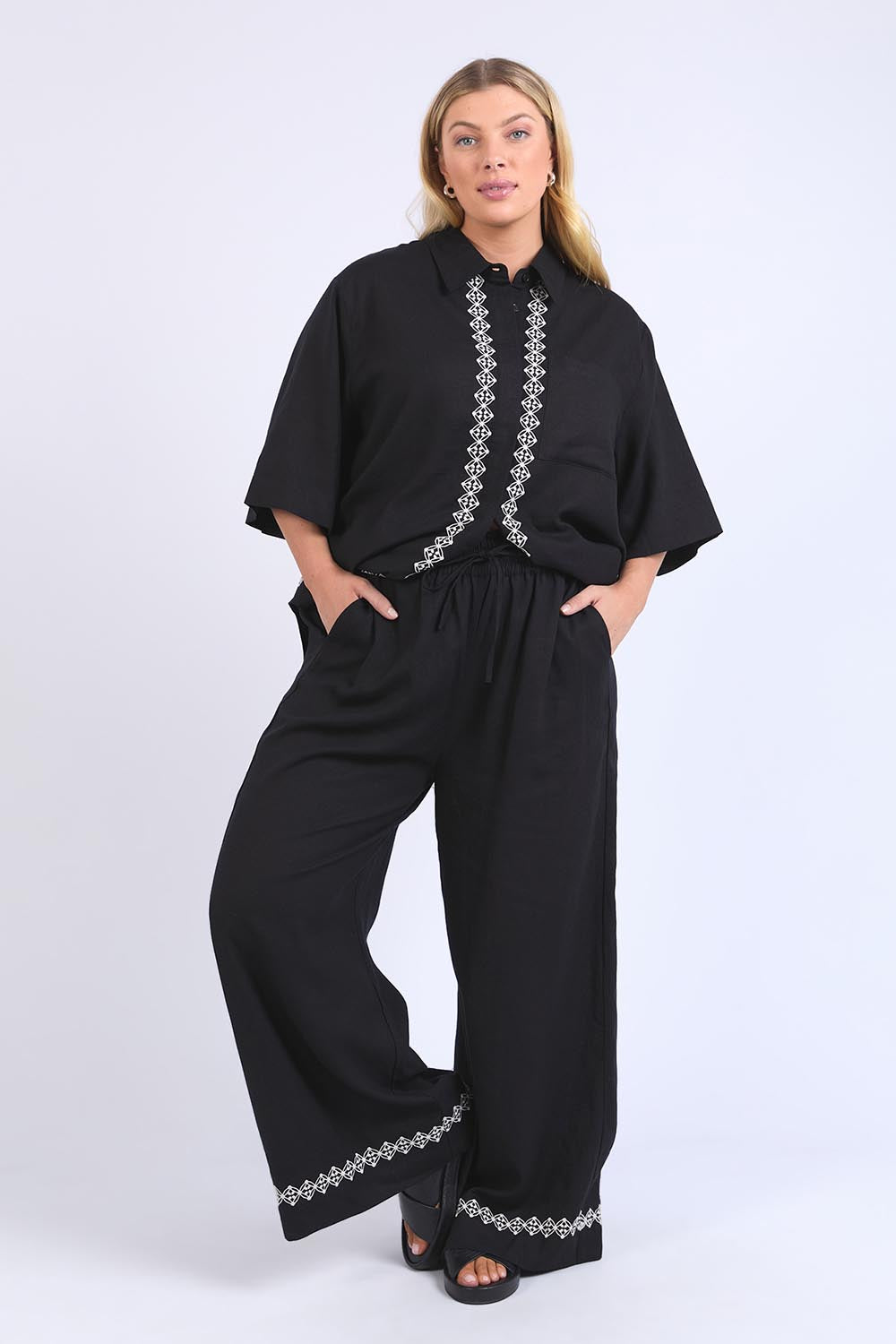 A model wearing the Nina Embroidered Pant in colour Black (Black), from the front, showing the whole outfit