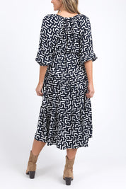 A model wearing the Gemma Geo Dress in colour Navygeo (Blue), from the back