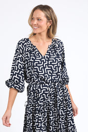 A model wearing the Gemma Geo Dress in colour Navygeo (Blue), from the front, cropped image