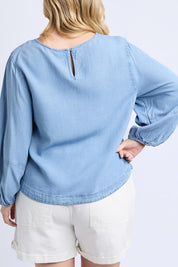 A model wearing the Della Lyocell Chambray Top in colour Midblue (Blue), from the back