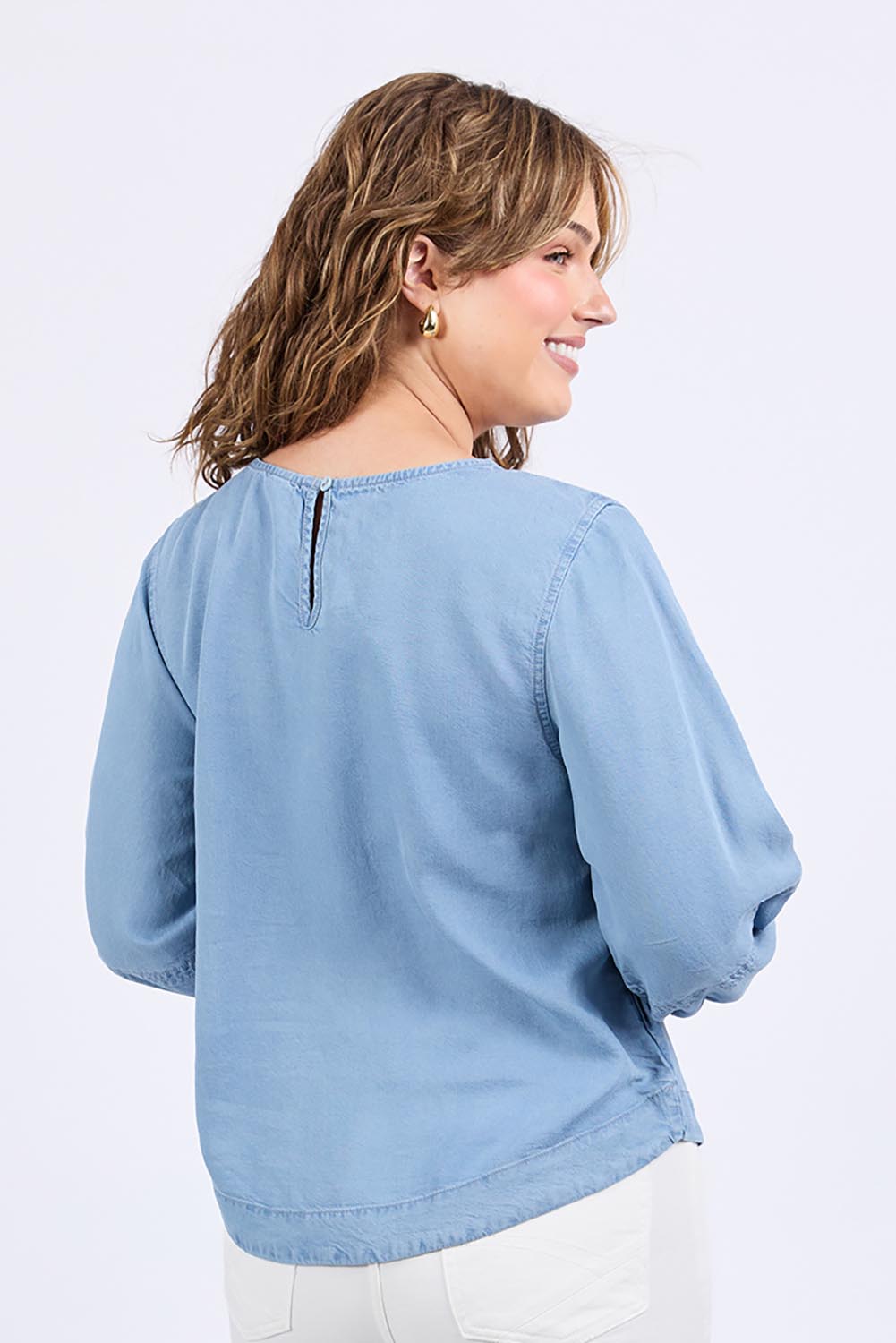 A model wearing the Della Lyocell Chambray Top in colour Midblue (Blue), from the back