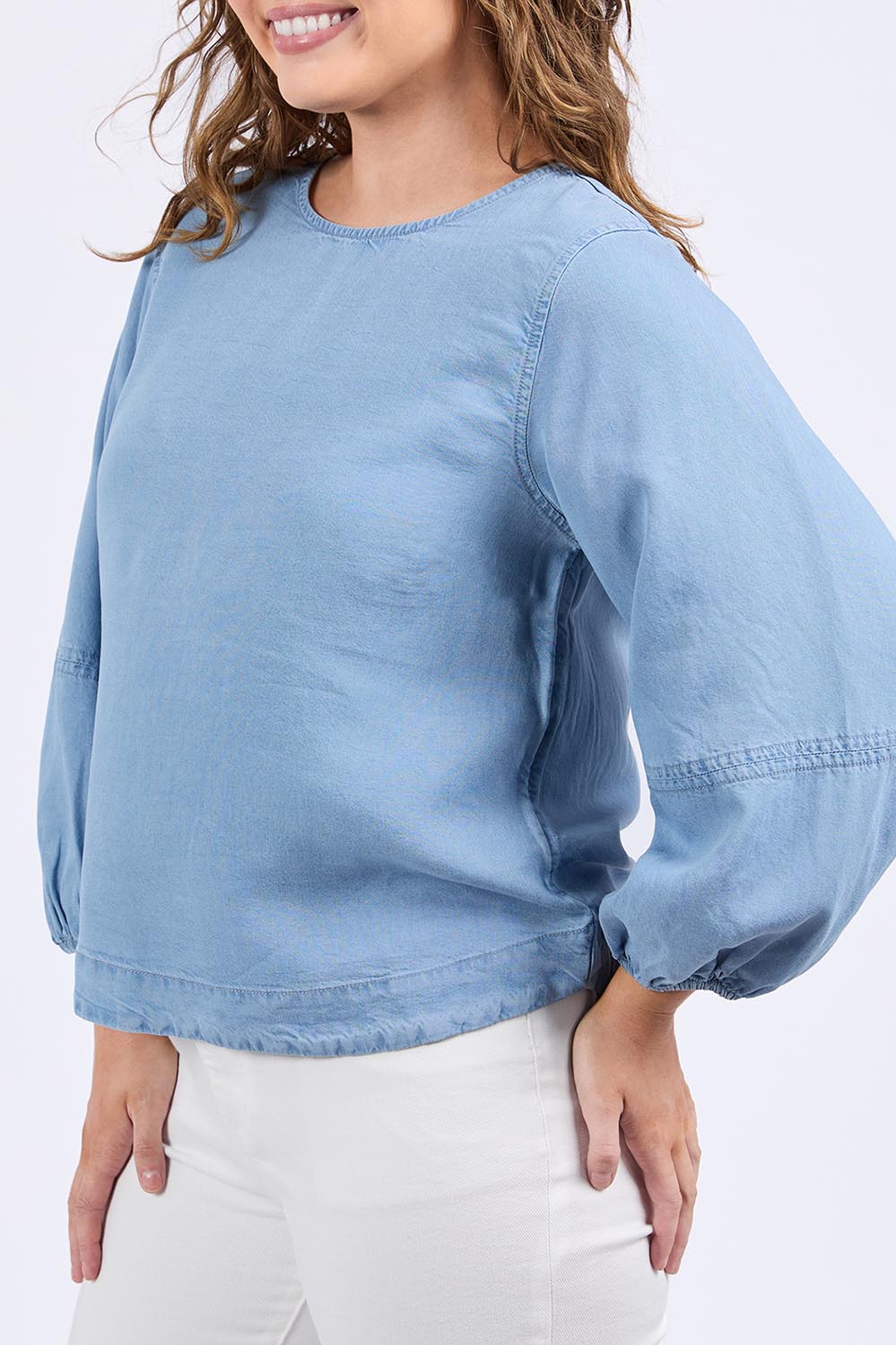 A model wearing the Della Lyocell Chambray Top in colour Midblue (Blue), from the front, cropped image