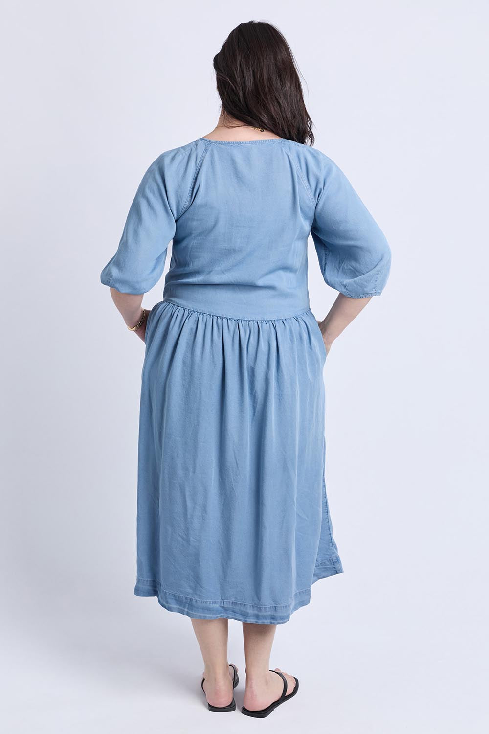 A model wearing the Sawyer Chambray Dress in colour Midblue (Blue), from the back