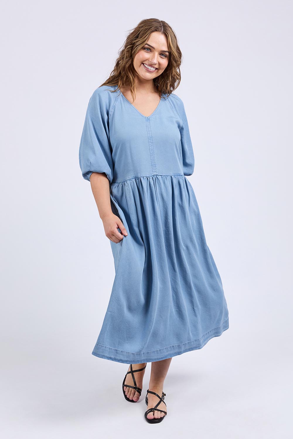 A model wearing the Sawyer Chambray Dress in colour Midblue (Blue), from the front, showing the whole outfit