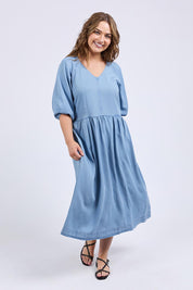 A model wearing the Sawyer Chambray Dress in colour Midblue (Blue), from the front, showing the whole outfit