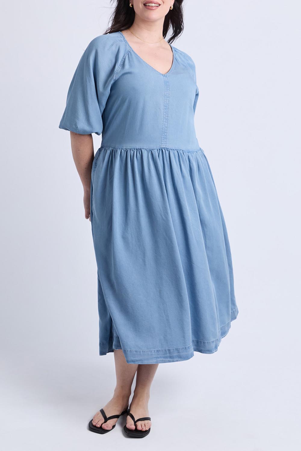 A model wearing the Sawyer Chambray Dress in colour Midblue (Blue), from the front, showing the whole outfit