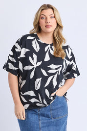 A model wearing the Mimosa Cotton Tee in colour Blackprint (Black), from the front, cropped image