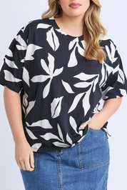 A model wearing the Mimosa Cotton Tee in colour Blackprint (Black), from the front, cropped image