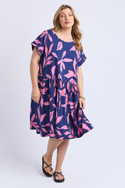 A model wearing the Mimosa Cotton Dress in colour Bluedepths, from the front, showing the whole outfit