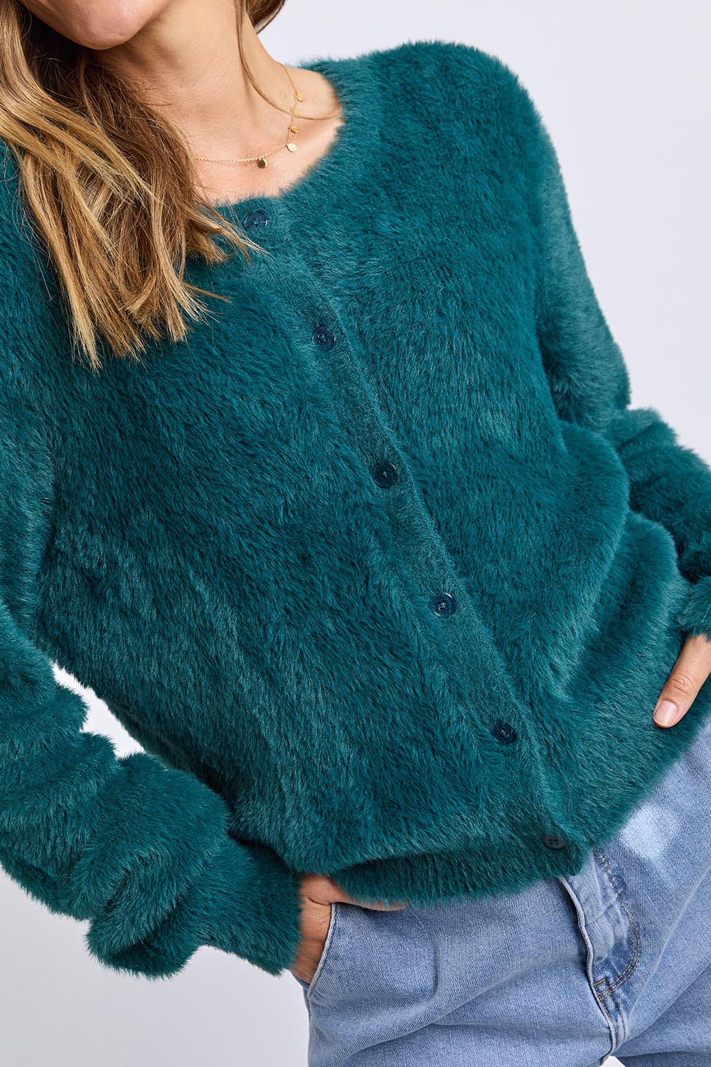 A model wearing the Paris Cardigan in colour Teal (Green), from the front, cropped image