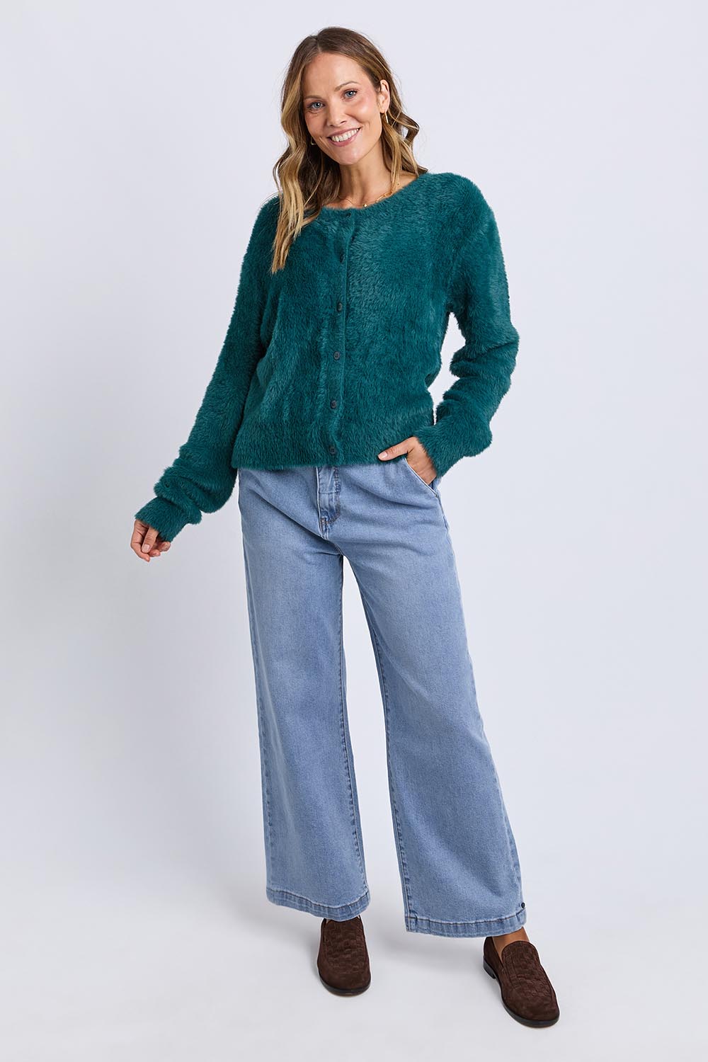 A model wearing the Paris Cardigan in colour Teal (Green), from the front, showing the whole outfit