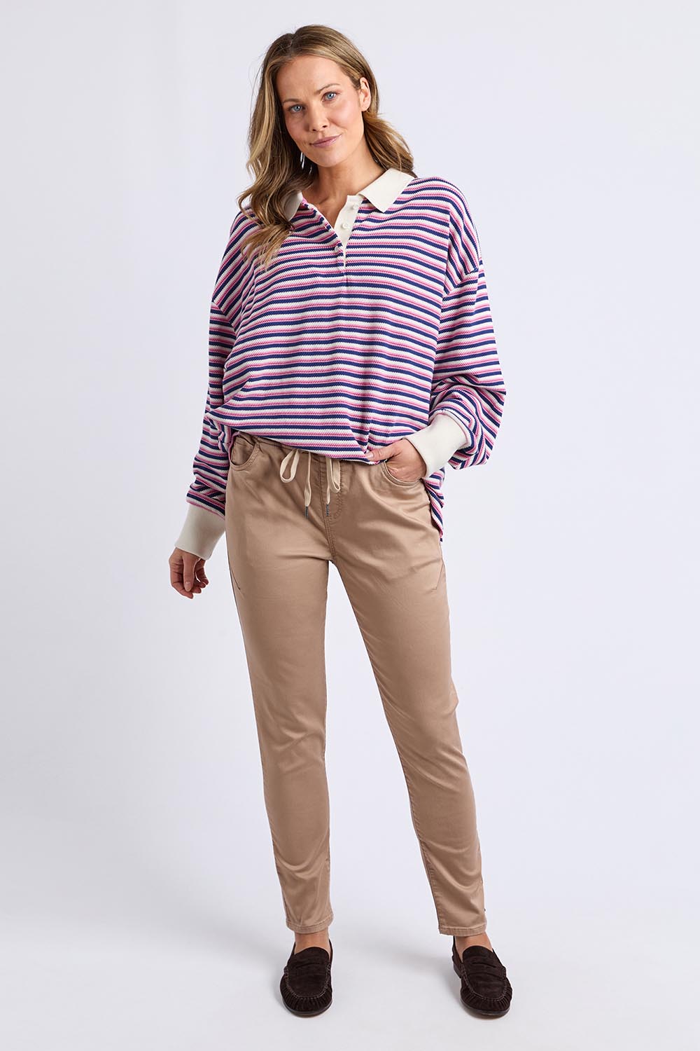 A model wearing the Riviera Polo Sweater in colour Navyred, from the front, showing the whole outfit