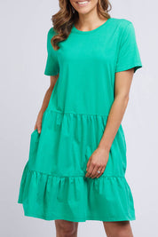 A model wearing the Joanna Tee Dress in colour Green (Green), from the front, cropped image