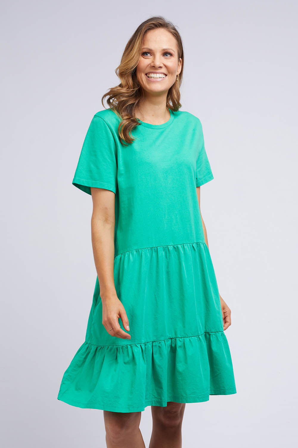 A model wearing the Joanna Tee Dress in colour Green (Green), from the front, cropped image