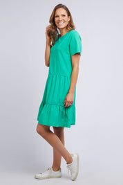 A model wearing the Joanna Tee Dress in colour Green (Green), from the front, showing the whole outfit