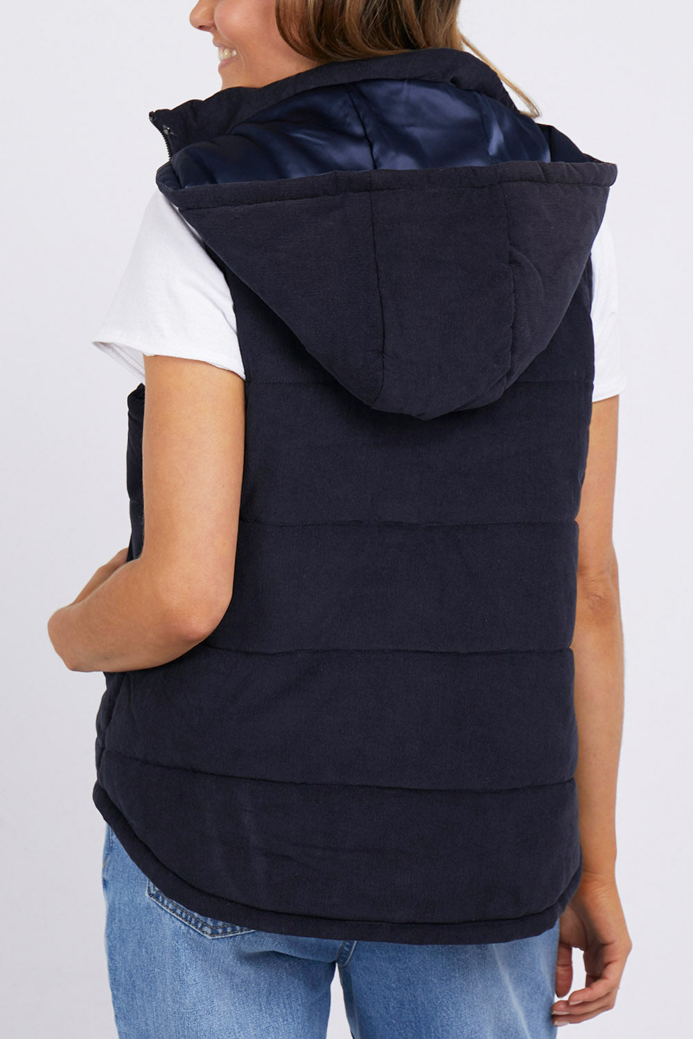A model wearing the Cord Puffer Vest in colour Dsapphire (Blue), from the back