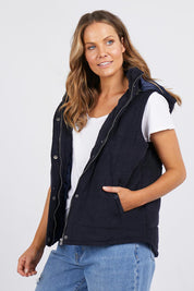 A model wearing the Cord Puffer Vest in colour Dsapphire (Blue), from the front, cropped image