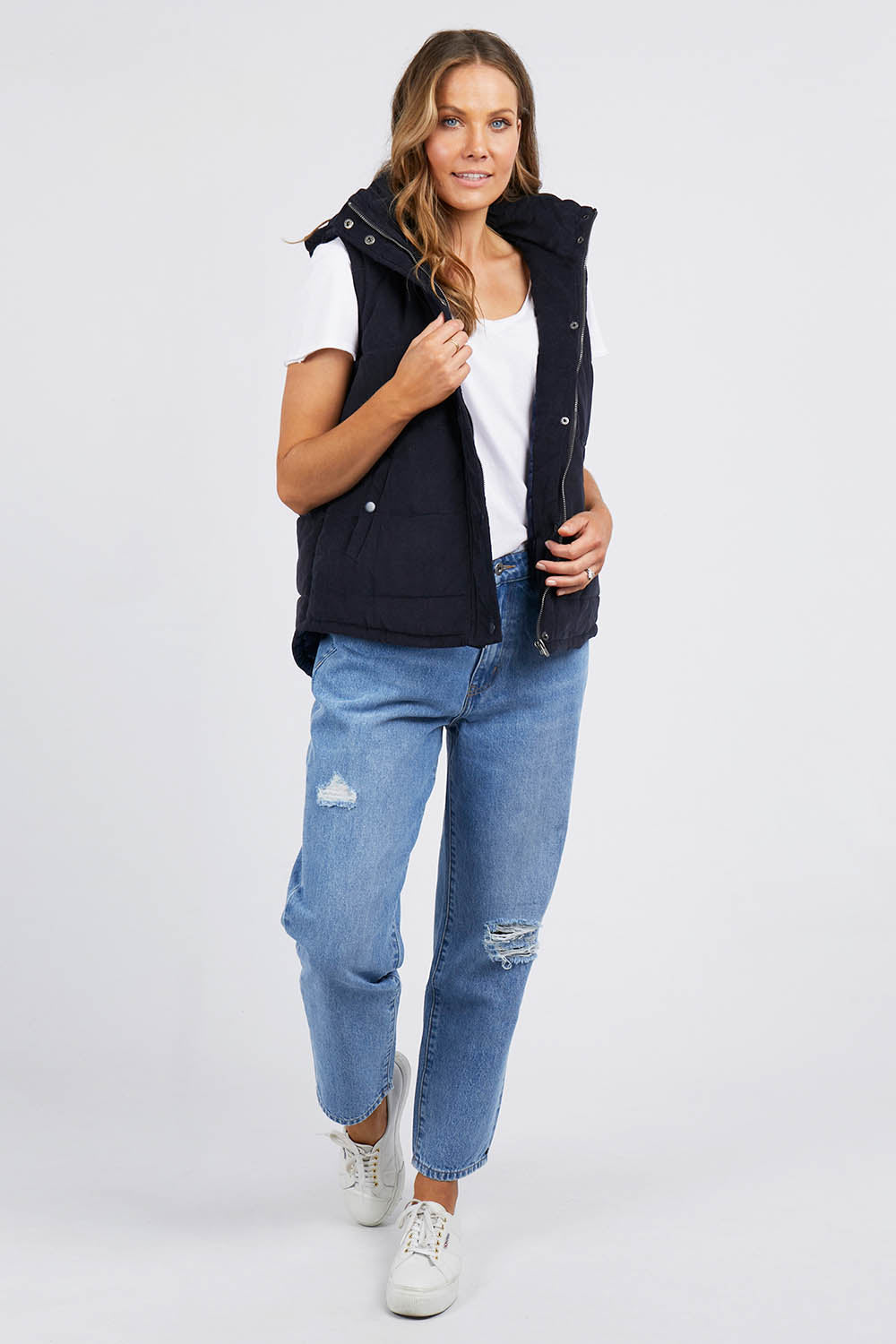 A model wearing the Cord Puffer Vest in colour Dsapphire (Blue), from the front, showing the whole outfit