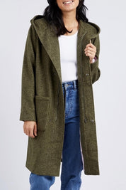 A model wearing the Jordan Coat in colour Clover (Green), from the front, cropped image