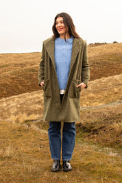 A model wearing the Jordan Coat in colour Clover (Green), from the front, showing the whole outfit