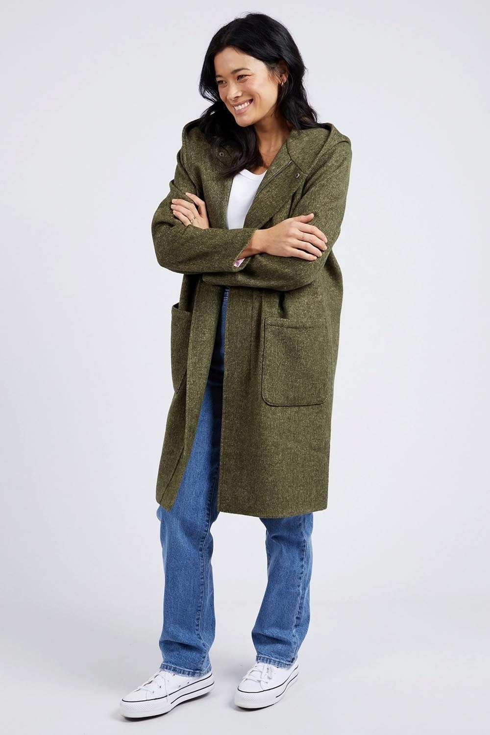 A model wearing the Jordan Coat in colour Clover (Green), from the front, showing the whole outfit
