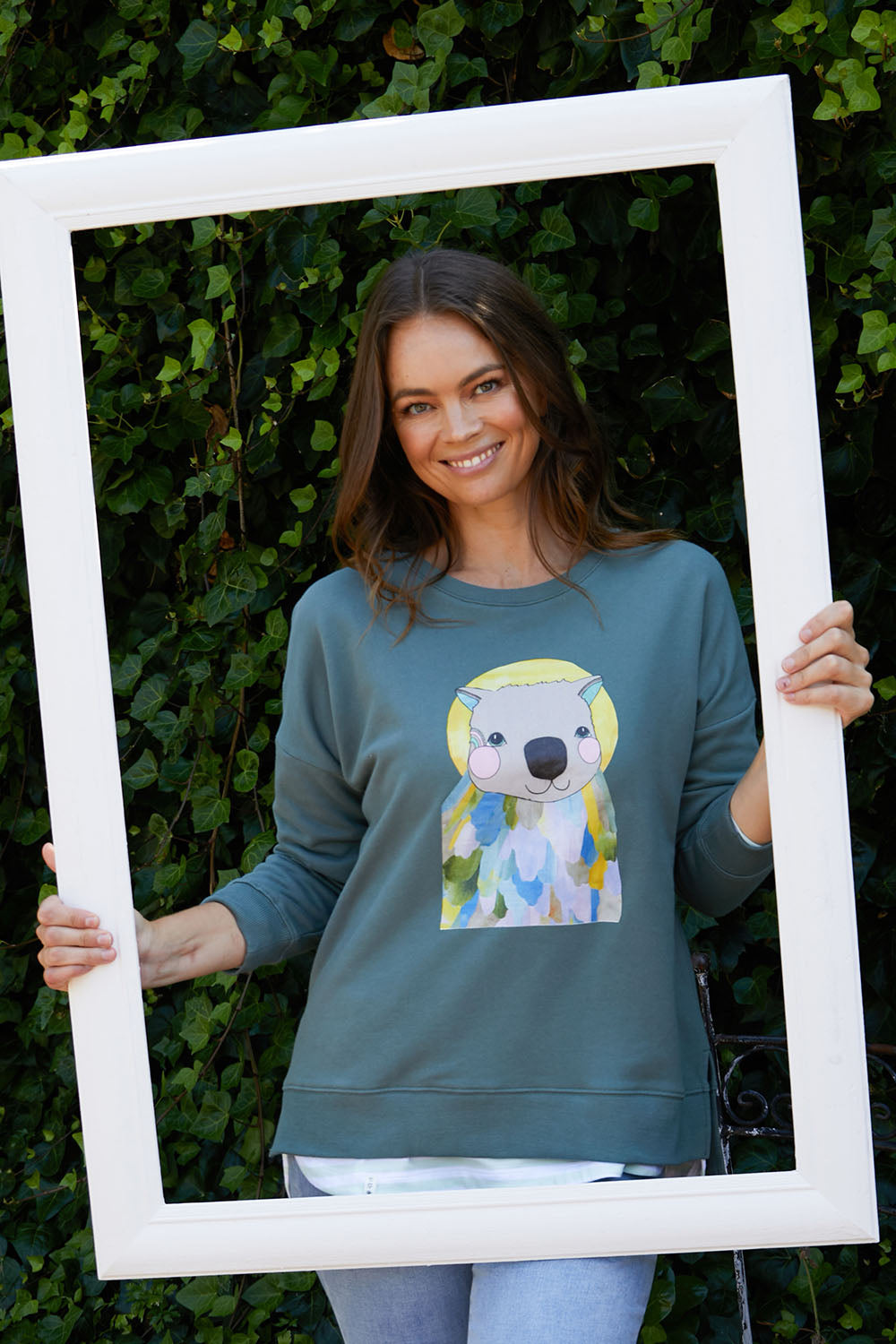 A model wearing the Laura Wombat Crew in colour Seapine (Green), from the front, showing the whole outfit