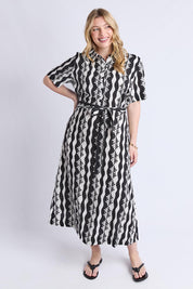 A model wearing the Casa Dress in colour Blackmarsh (Black), from the front, showing the whole outfit