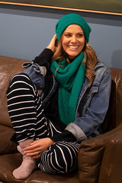 A model wearing the Snug Scarf in colour Wintgreen (Green), from the front, showing the whole outfit