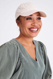 Model Olivia wearing size OneSize of the Elm Cap in colour Oatmeal, from the front, showing the whole outfit
