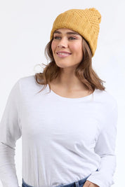 A model wearing the Berry Beanie in colour Mustard, from the front, cropped image