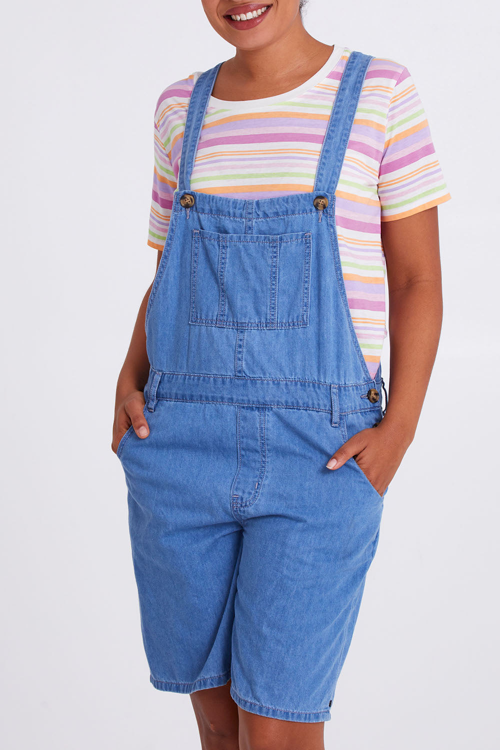 Model Olivia wearing size 10 of the Maltilda Short Denim Overalls in colour Midblue (Blue), from the front, cropped image