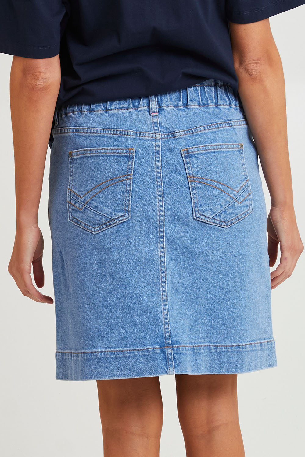 Model Madeline wearing size 10 of the Atlas Denim Skirt in colour Midblue (Blue), from the back