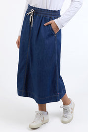 A model wearing the Fundamental Greta Denim Skirt in colour Darkblue (Blue), from the front, cropped image