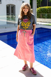 A model wearing the Greta Denim Skirt in colour Chateauros (Pink), from the front, showing the whole outfit