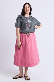 A model wearing the Greta Denim Skirt in colour Chateauros (Pink), from the front, showing the whole outfit