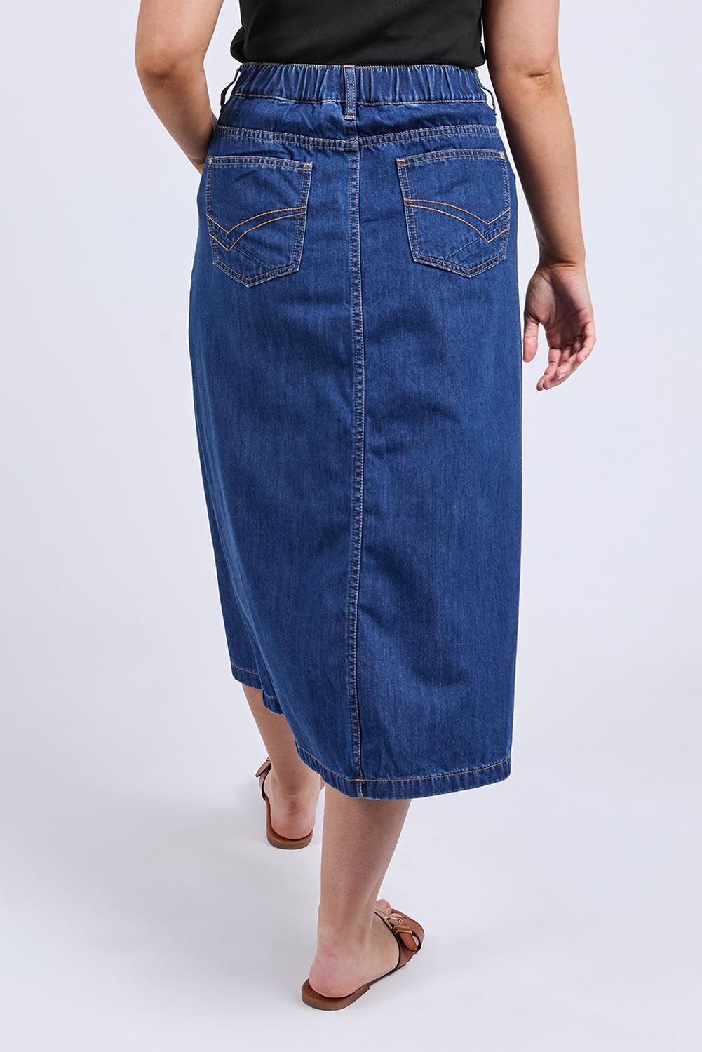 A model wearing the Scallop Edge Denim Skirt in colour Midblue (Blue), from the back