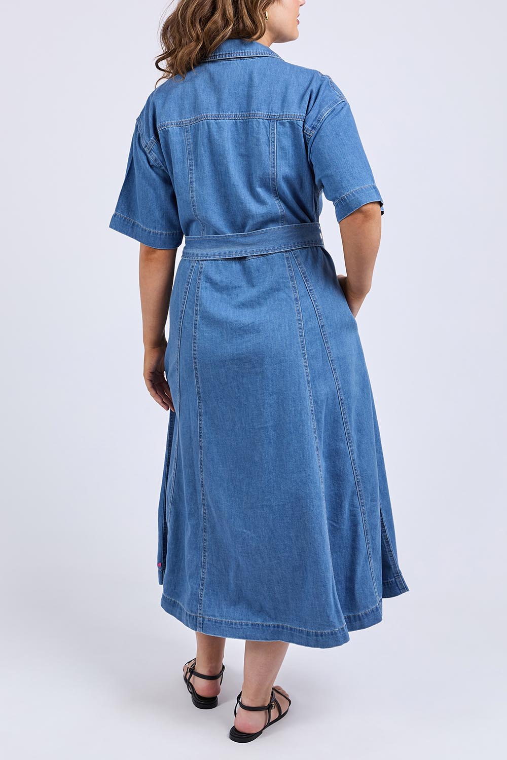 A model wearing the River Denim Dress in colour Midblue (Blue), from the back