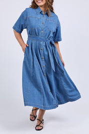 A model wearing the River Denim Dress in colour Midblue (Blue), from the front, cropped image