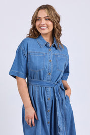 A model wearing the River Denim Dress in colour Midblue (Blue), from the front, cropped image